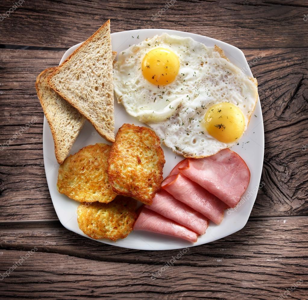 Breakfast - fried eggs with ham and pieces of bread. — Stock Photo