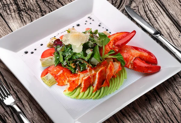 Салат з омарами на білій тарілці на дерев'яному столі . — стокове фото