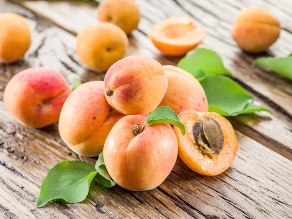 Apricots and its cross-section on the old wooden table. — Stock Photo, Image