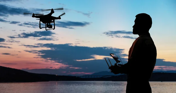 Homem voando um drone perto do litoral ao pôr do sol . — Fotografia de Stock