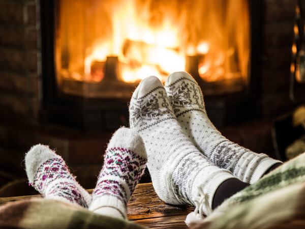 Warming and relaxing near fireplace. Woman and child feet in fro