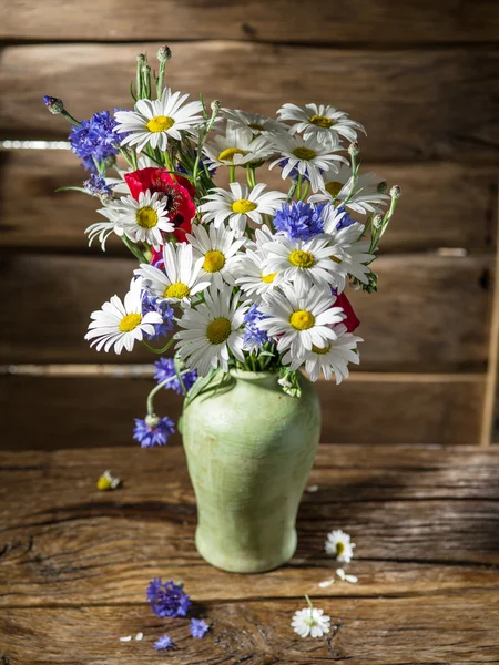 Bukiet pole kwiatów w wazonie na drewnianym stole. — Zdjęcie stockowe