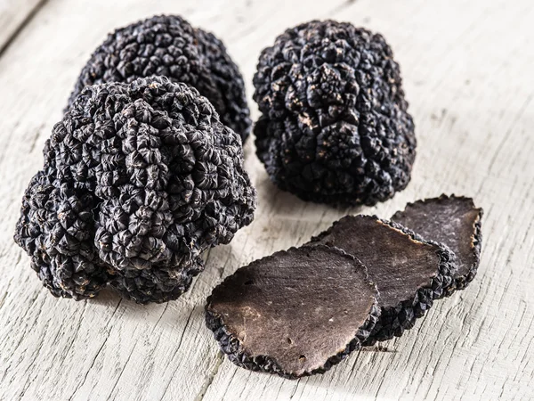 Trufas pretas na velha mesa de madeira. — Fotografia de Stock