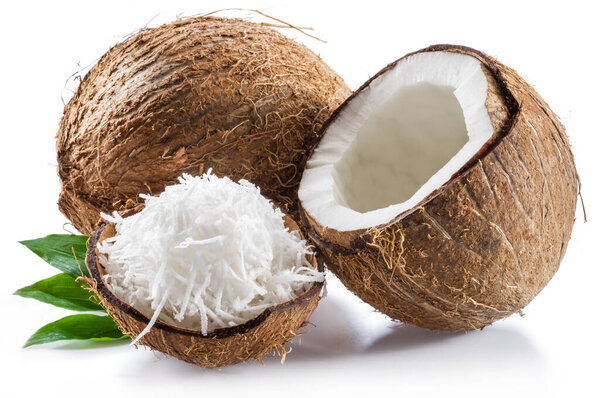 Cracked coconut fruit with white flesh and shredded coconut flakes isolated on white background.