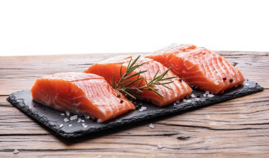 Siyah kesme tahtasında taze somon filetosu otlar ve baharatlarla.