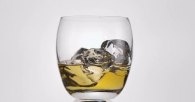 Viski ve buzlu bardak beyaz bir zemin üzerinde yavaşça saat yönünde döner.