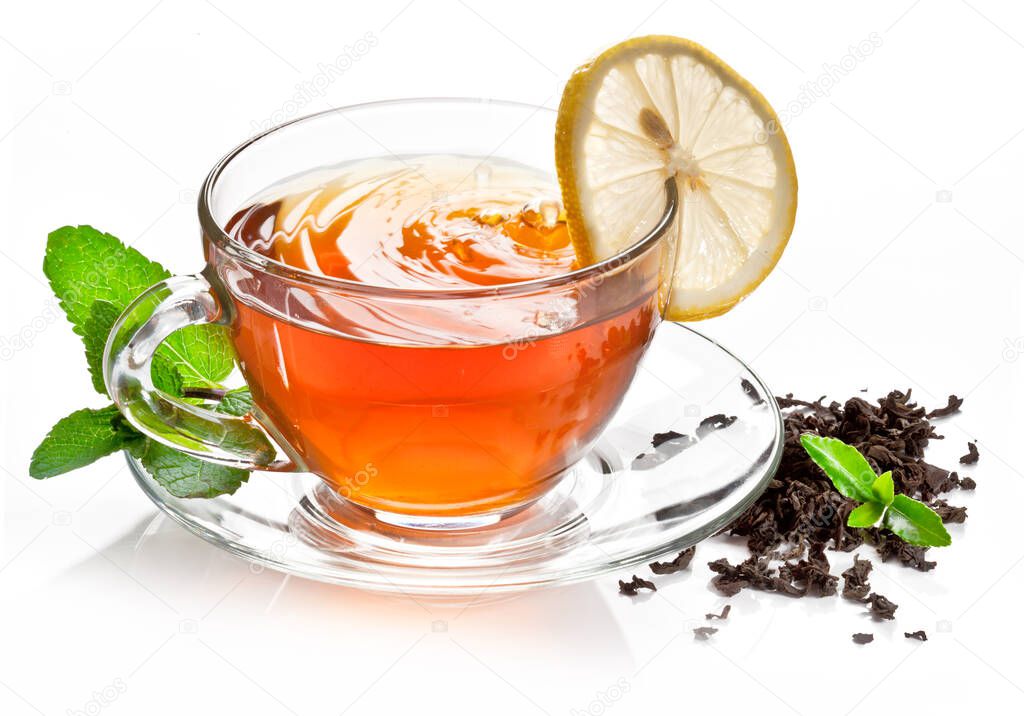 Glass cup with black tea, a slice of lemon and mint leaves isolated on a white background.
