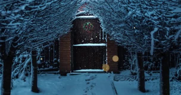 慢慢地走到门口 晚上装饰着圣诞装饰品 美丽的树木环绕着 下着雪 神秘的灯光也在飞扬 圣诞钟声在敲响 — 图库视频影像