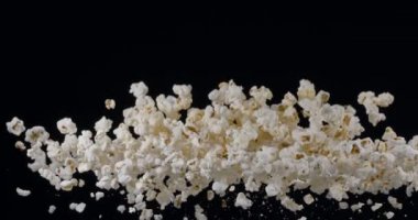 Patlamış mısır taneleri yavaşça yükselir ve siyah arka plana düşer. Blackmagic Ursa Pro G2, 300 fps. 