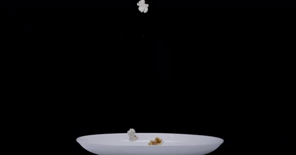 Popcorn Vločky Pomalu Padají Bílý Talíř Černém Pozadí Blackmagic Ursa — Stock video