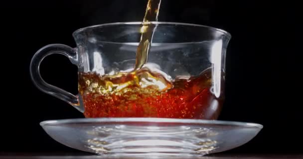 Chá Lentamente Derramado Uma Xícara Vidro Bule Chá Fundo Preto — Vídeo de Stock