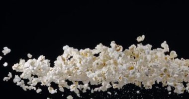 Patlamış mısır taneleri yavaşça yükselir ve siyah arka plana düşer. Blackmagic Ursa Pro G2, 300 fps. 