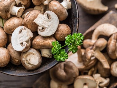 Ahşap masa üzerinde farklı kahverengi yenilebilir mantarlar ve şifalı otlar. Üst görünüm.