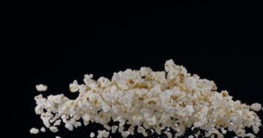 Patlamış mısır taneleri yavaşça yükselir ve siyah arka plana düşer. Blackmagic Ursa Pro G2, 300 fps. 