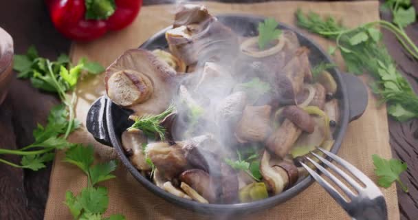 烤锅与油炸香菇站在古老的木制桌子上 放出蒸汽 人的手拿起一个用叉子的蘑菇 — 图库视频影像