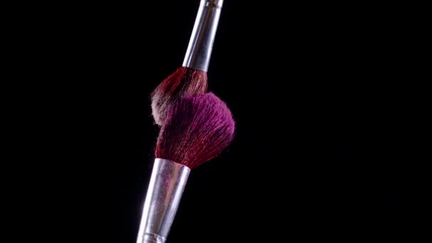 两把化妆刷相撞 造成粉色粉末颗粒在黑色背景下旋转 慢动作 每秒300英尺 — 图库视频影像