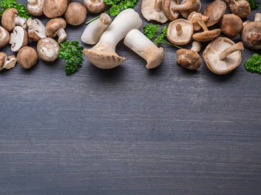 Siyah masada farklı kahverengi, yenilebilir mantarlar ve şifalı bitkiler. Üst görünüm.