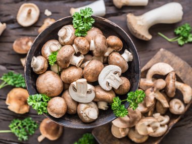 Ahşap masa üzerinde farklı kahverengi yenilebilir mantarlar ve şifalı otlar. Üst görünüm.