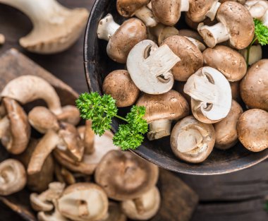 Ahşap masa üzerinde farklı kahverengi yenilebilir mantarlar ve şifalı otlar. Üst görünüm.