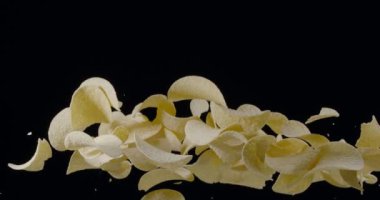 Doğal patates cipsi siyah arka planda yükselip alçalır. Yavaş Hareket 300 fps Blackmagic Ursa Pro G2.