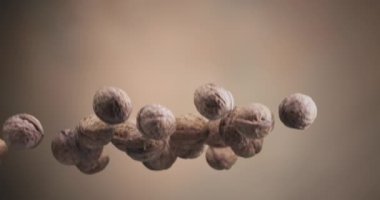 Birkaç ceviz yavaşça yükselir ve açık kahverengi bir zemine düşer. Yavaş çekim 300 fps. 