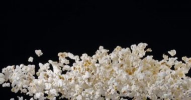 Patlamış mısır taneleri yavaşça yükselir ve siyah arka plana düşer. Blackmagic Ursa Pro G2, 300 fps. 