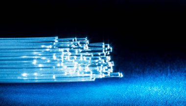 Ucunda ışık olan bir yığın optik iplik. Mavi arkaplan.