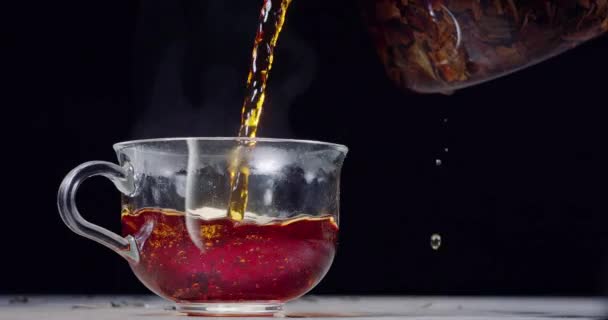 Vierte Lentamente Una Taza Vidrio Una Tetera Sobre Fondo Negro — Vídeo de stock