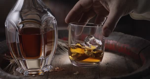 スーツの男 ソムリエ ヴィンテージのウイスキー樽から氷の上にウイスキーのガラスを取り ガラスを振るとウイスキーの匂いを広めるために — ストック動画