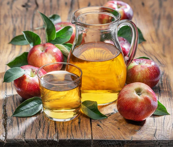 Koyu eski ahşap masada taze elma suyu ve organik elmalar..