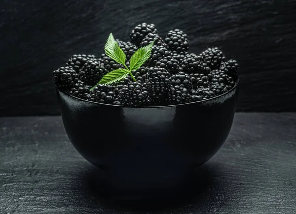 Gri masada olgun böğürtlenli siyah kase.