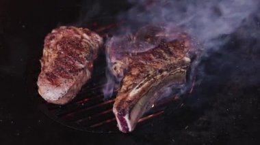 Izgara ızgarada baharatlı pirzola biftekleri ve alevli bir ateş. Yavaş kamera dönüşü. 4K ağır çekim.