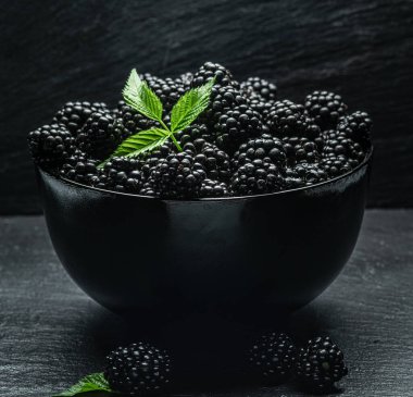 Gri masada olgun böğürtlenli siyah kase.