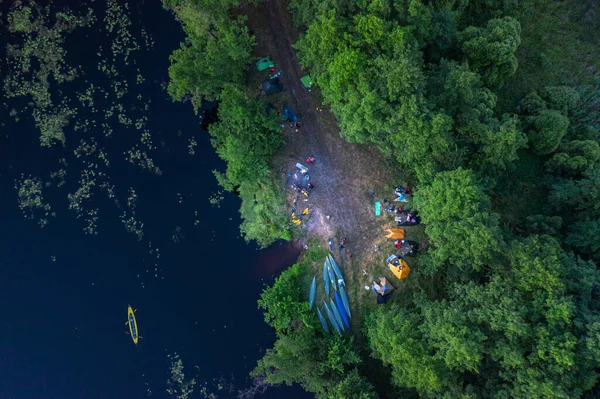 Canoes and camp on the bank of the river. Top view. Beautiful picture of river and green banks of the river in the summer morning day.