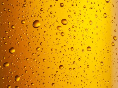 Soğutulmuş bir bardak bira. Bira bardağının soğuk yüzeyine küçük su damlaları düşer..