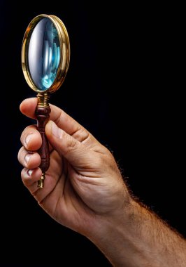 Siyah arka planda izole edilmiş bir adamın elinde eski moda büyüteç ya da el lensi..