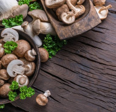 Ahşap masa üzerinde farklı kahverengi yenilebilir mantarlar ve şifalı otlar. Üst görünüm.