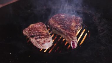 Izgara ızgarada baharatlı pirzola biftekleri ve alevli bir ateş. Yavaş kamera dönüşü. 4K ağır çekim.
