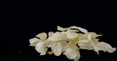 Doğal patates cipsi siyah arka planda yükselip alçalır. Yavaş Hareket 300 fps Blackmagic Ursa Pro G2.