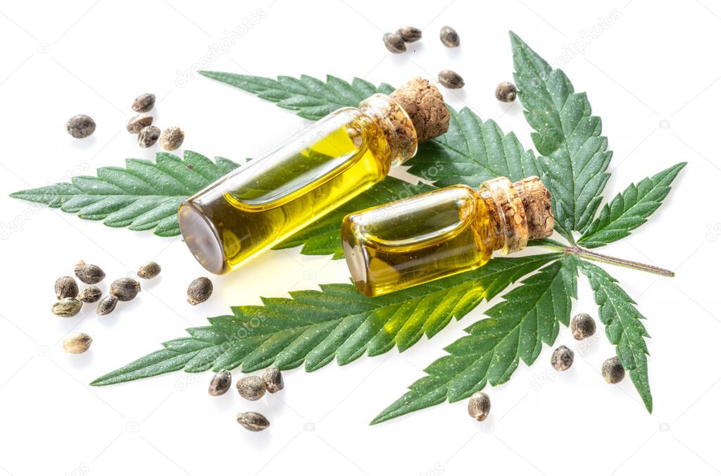 Cannabis leaf and small bottles of hemp oil isolated on white background. Close up.