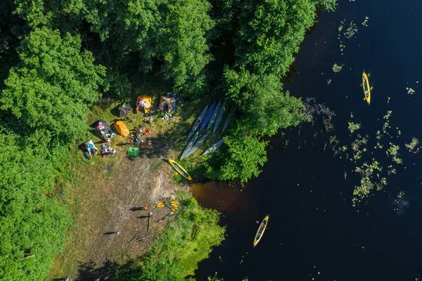 Canoes on the calm river and camp on the bank of the river. Top view. Beautiful picture of river and green banks of the river in the summer morning day.