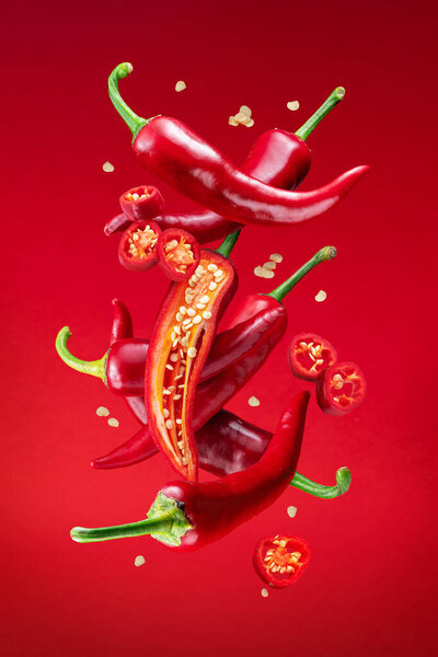 Fresh red chilli peppers and cross sections of chilli pepper with seeds floating in the air. File contains clipping paths.