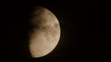 Tamamlanmamış Ay, gece gökyüzünde küçük bulutlar eşliğinde hareket eder..