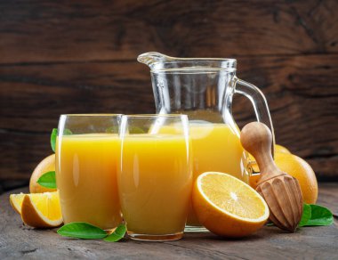 Sarı portakal meyveleri ve koyu ahşap arka planda izole edilmiş taze portakal suyu..