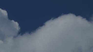 Yakın plan 4K hızlandırılmış mavi güneşli gökyüzünde beyaz büyük bulutların videosu. Yaz mavi bulutlu gökyüzü zaman atlaması. Bulutların arasında bir uçak uçurmanın etkisi.