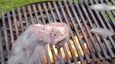 Pirzola bifteklerini ızgarada ızgaraya baharatla kızgın bir ateşle fırlat. 4K ağır çekim.