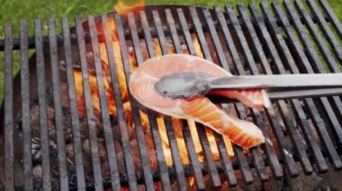 Somon bifteğini ızgarada ızgarada, alevli bir ateşte pişir. 4K ağır çekim. 