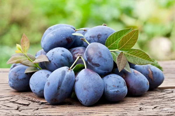 Plums on an old wooden table. — Stock Photo, Image