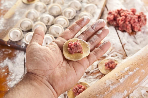 Dumplings. Dough with meat filling on the cook's hands. — Stock Photo, Image