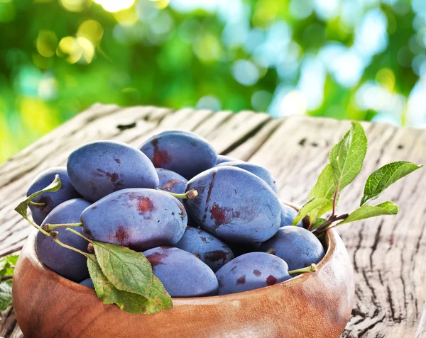 Plums on an old wooden table. — Stock Photo, Image